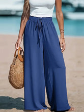 Charger l'image dans la galerie, Pantalon large style vacances pour femme : taille haute élastique avec cordon de serrage, coupe ample et droite, idéal pour la plage ou la détente.
